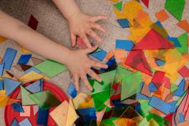 Mange fargede, gjennomsiktige små trekanter og en barnehånd 