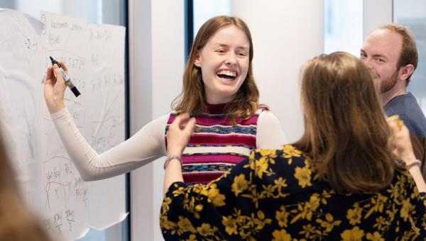 Lærere som ler og skriver på vertikal tavle